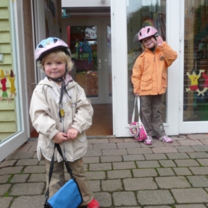 Zwei Kinder mit Fahrradhelm vor dem Eingang einer Kita